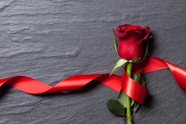 Rosa roja sobre un fondo de pizarra con una cinta roja