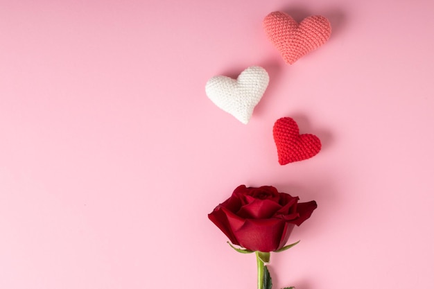 Una rosa roja y tres corazones sobre un fondo rosa Banner para la postal del día de San Valentín para el 14 de febrero Minimalismo de amor