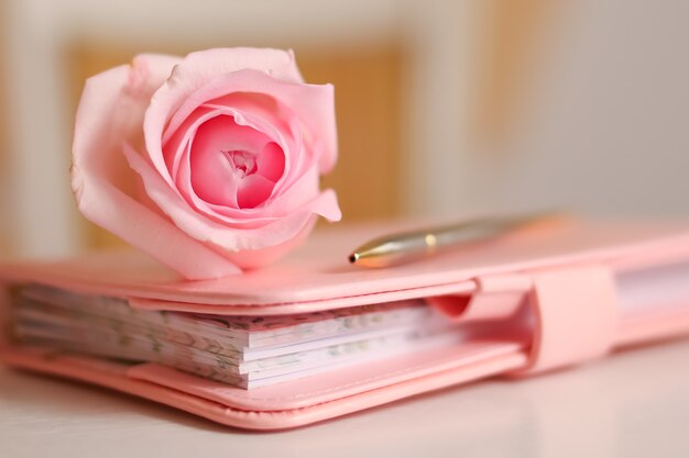 Rosa rosa em um caderno fechado romance e delicadas cores pastel para uma festa de casamento ou o nascimento de uma menina