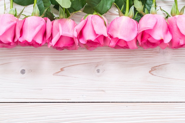 Foto rosa rosa em um vaso no fundo de madeira