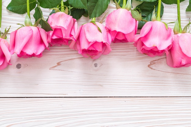 rosa rosa en el florero sobre fondo de madera