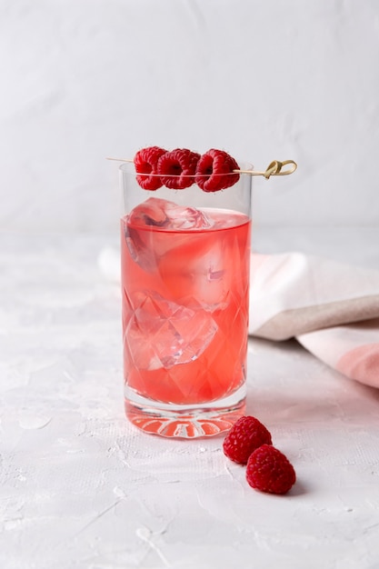 Rosa rosa gelado cocktail com framboesa em copo de cristal na mesa