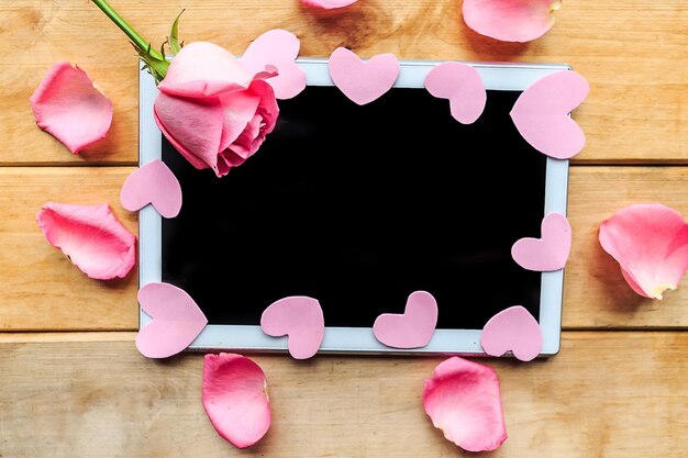 Rosa Rosen und dekorative Herzen auf der Mockup-Tablette Valentinstag Hochzeit oder Muttertag Grußkarte Kopieren Sie Platz für den Text