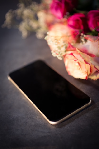 Rosa Rosen und Smartphone auf dem Tisch