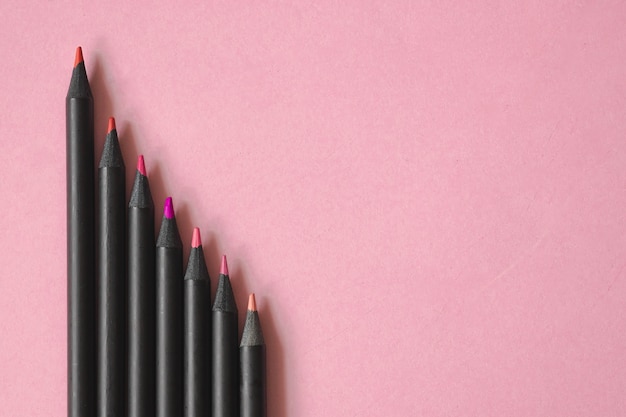 Rosa, rote und violette Tonfarbe von schwarzen Bleistiften auf Pastellrosa Hintergrund