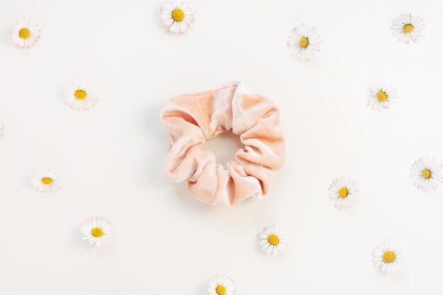 Rosa Samt-Scrunchie und Gänseblümchen-Frühlingsblumen auf weißem Hintergrund