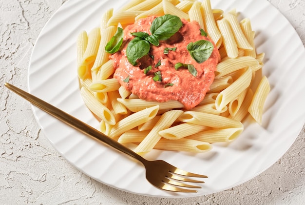 Rosa Sauce Pasta Parma Rosa Sauce mit Penne auf einem Teller mit goldener Gabel