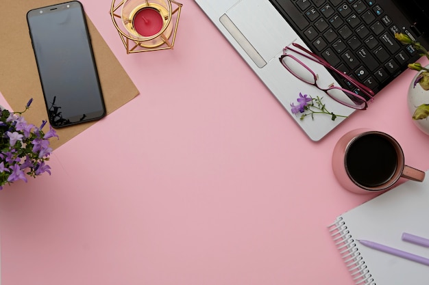 Rosa Schreibtisch des modernen Arbeitsplatzes der flachen Lage mit Laptop, Gläsern, Smartphone, Kaffeetasse.