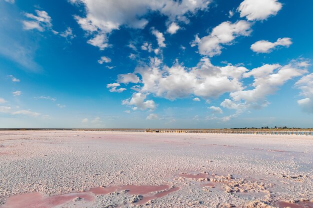 Rosa See und Sandstrand mit Meeresbucht unter blauem Himmel mit Wolken