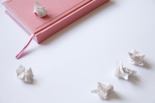 Rosa Tagebuch auf weißen und zerknitterten Papierstücken