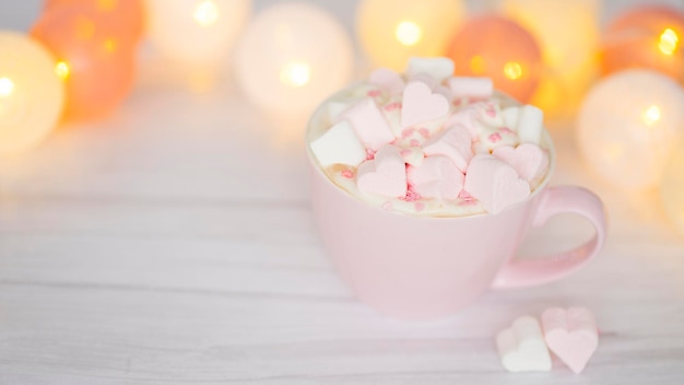 Rosa Tasse mit Kakao und herzförmigen Marshmallows