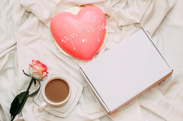 Rosa de té rosa con pastel de mousse rosa en forma de corazón con caja de regalo