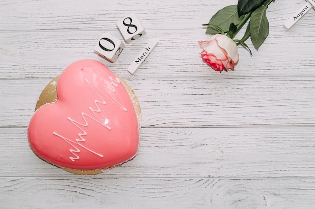 Rosa de té rosa con pastel de mousse rosa en forma de corazón y calendario del 14 de febrero