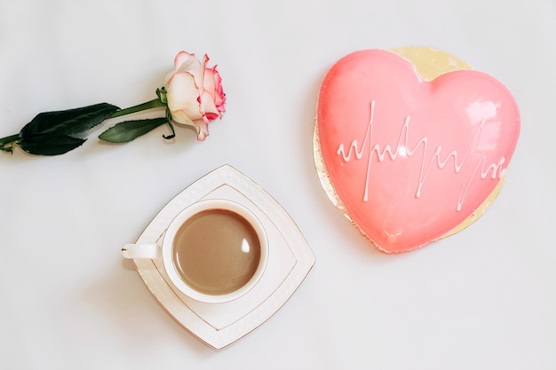 Rosa de té rosa con pastel de mousse rosa en forma de corazón con una taza de café