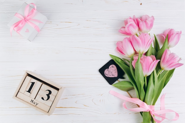 Rosa Tulpen, Kalender und Geschenk auf einem weißen hölzernen Hintergrund