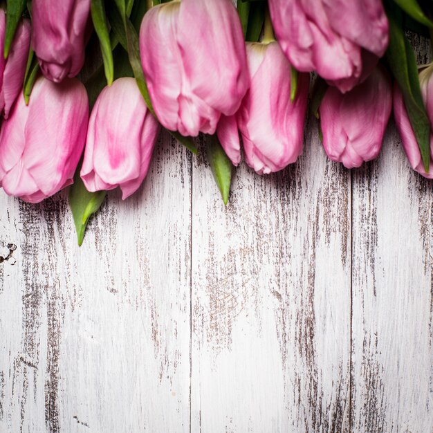 Rosa Tulpen über schäbigem weißen Holztisch