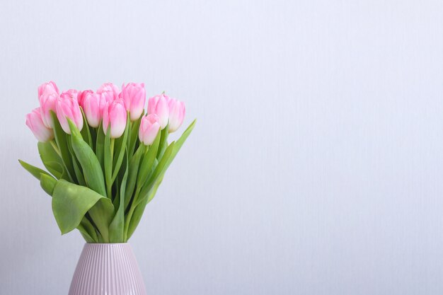 Rosa Tulpenblumenstrauß in der Vase auf grauem Hintergrund.