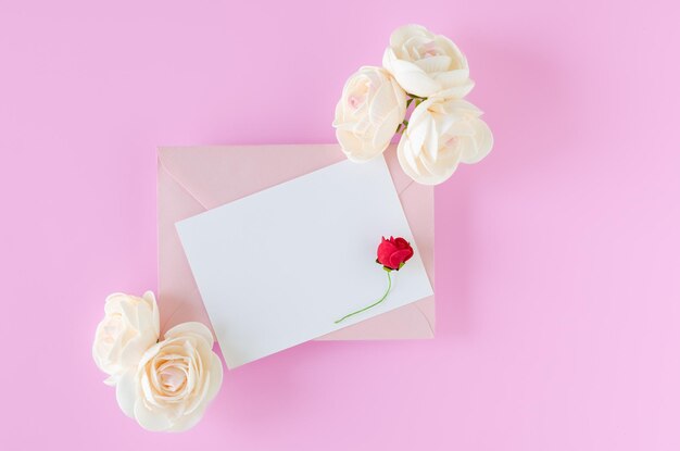 Rosa Umschlag mit Karte und Rosen auf weißem Hintergrund