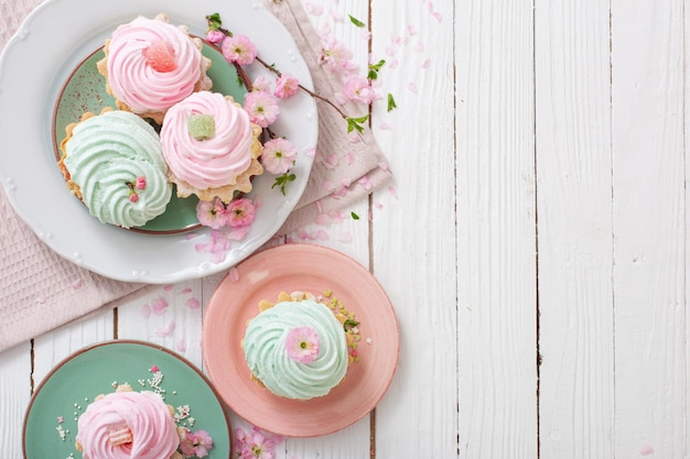 Rosa und grüne Cupcakes mit Frühlingsblumen auf weißem Holzhintergrund