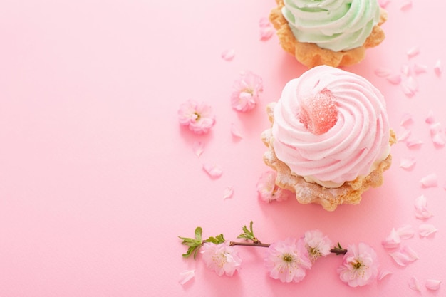 Rosa und grüne kleine Kuchen mit Frühlingsblumen auf rosa Hintergrund