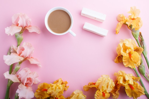 Rosa und orange Irisblumen und ein Tasse Kaffee