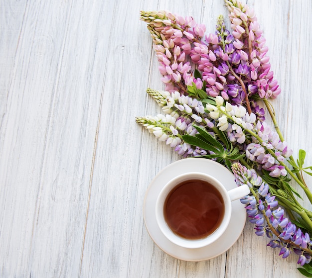 Rosa und purpurrote Lupineblumen und Tasse Tee Draufsicht