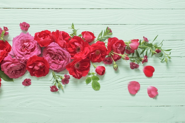 Rosa und rote Rosen auf grünem Holzhintergrund
