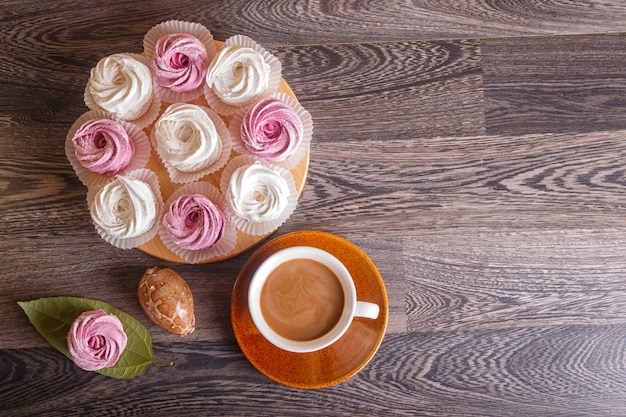 Rosa und weiße Eibische (Zefir) mit Tasse Kaffee auf einem grauen hölzernen Hintergrund