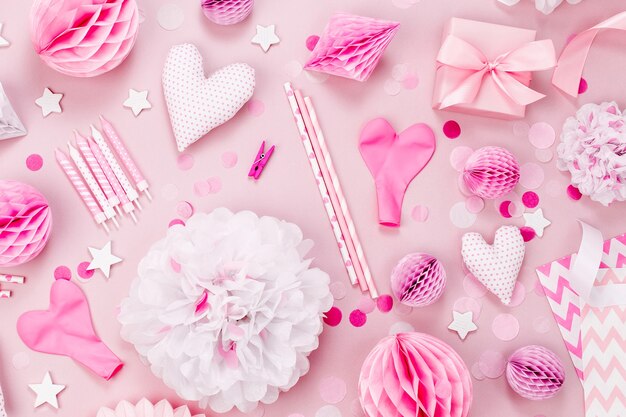 Rosa und weiße Papierdekorationen, Pompons, Süßigkeiten, Herzen, Geschenke, Konfetti für die Babyparty. Geburtstag Konzept. Flache Lage, Ansicht von oben