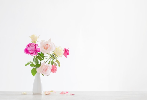 Rosa und weiße Rosen in weißer Keramikvase auf weißem Hintergrund