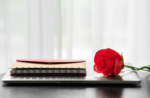 Rosa vermelha e o laptop no convés, conceito dos namorados