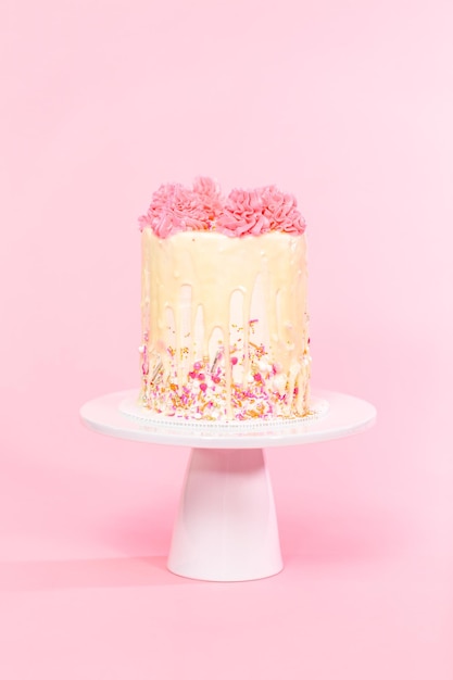 Foto rosa-weiße buttercreme-creme-torte mit rosa streuseln und weißem schokoladen-ganache-tropf.