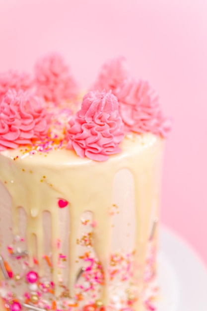 Rosa-weiße Buttercreme-Creme-Torte mit rosa Streuseln und weißem Schokoladen-Ganache-Tropf.