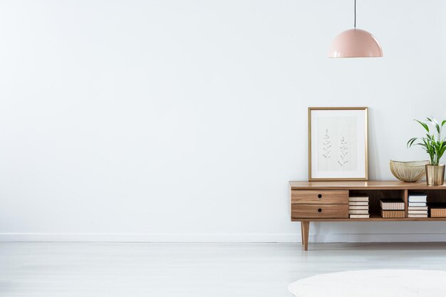 Rosafarbene Lampe über einem Sideboard aus Holz