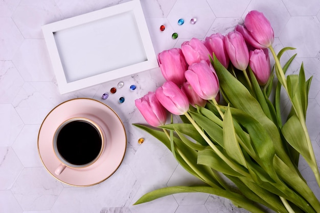 Rosafarbene Tulpen, schwarzer Laptop, Telefon, Kopfhörer und Fotorahmen auf hellem Hintergrund