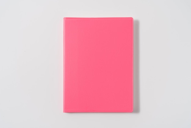 Rosafarbenes Notizbuch auf weißem Schreibtisch. Business-Minimalkonzept für Frauen. Flacher Kopierraum mit Draufsicht