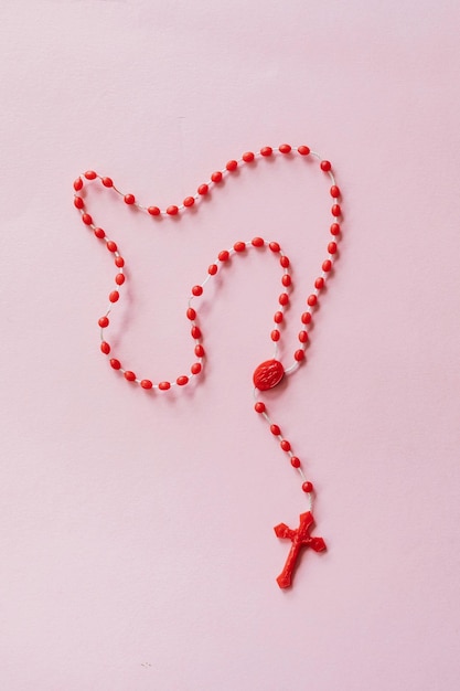 Foto rosario rojo en superficie rosada foto de archivo