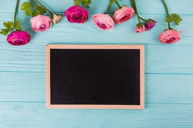 Rosarosenblumen mit Tafel auf Holztisch