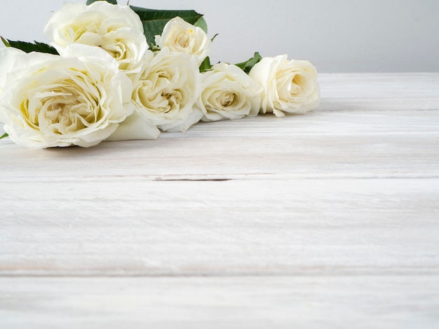 Rosas blancas sobre una mesa de madera blanca.