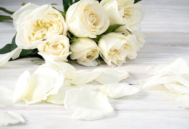 Rosas blancas sobre una mesa de madera blanca.