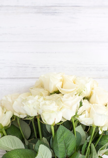 Foto rosas brancas sobre um fundo branco de madeira. buquê de rosas brancas