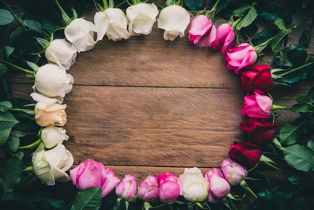 Rosas de colores alineados en un piso de madera con espacio para escribir su mensaje.