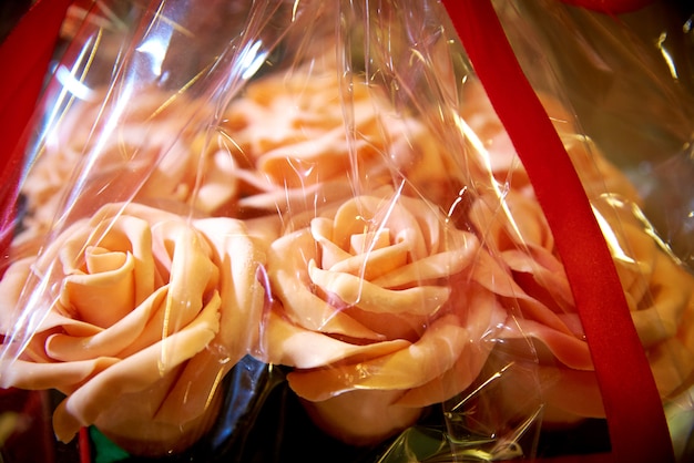Rosas comestibles de un ramo del chocolate blanco en primer del envoltorio para regalos.