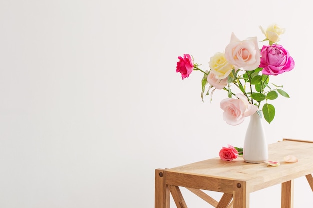 Rosas cor de rosa e brancas em vaso cerâmico branco sobre fundo branco