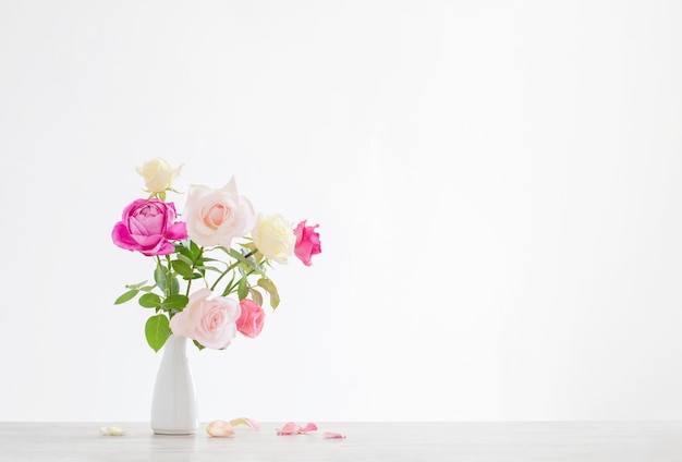 Rosas cor de rosa e brancas em vaso cerâmico branco sobre fundo branco