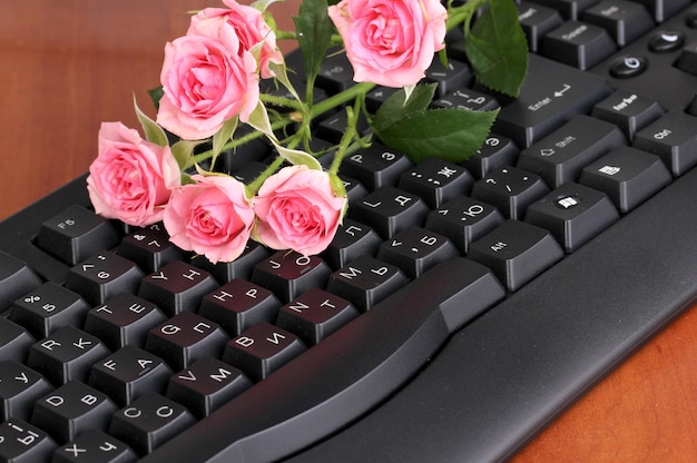 Rosas cor de rosa em close-up de teclado para comunicação com a Internet