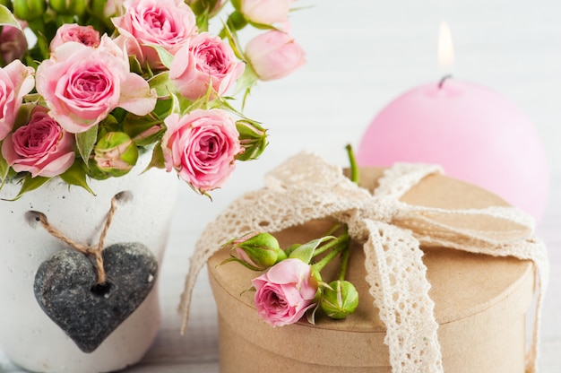 Rosas cor de rosa em panela de concreto com vela