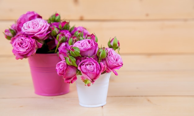 Rosas cor de rosa em um vaso com fundo de madeira e