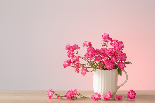 Rosas cor de rosa em vaso de cerâmica no fundo rosa