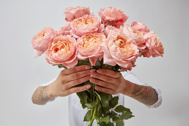 Rosas cor de rosa. Mulher segurando um buquê de rosas em um fundo cinza, dia dos namorados